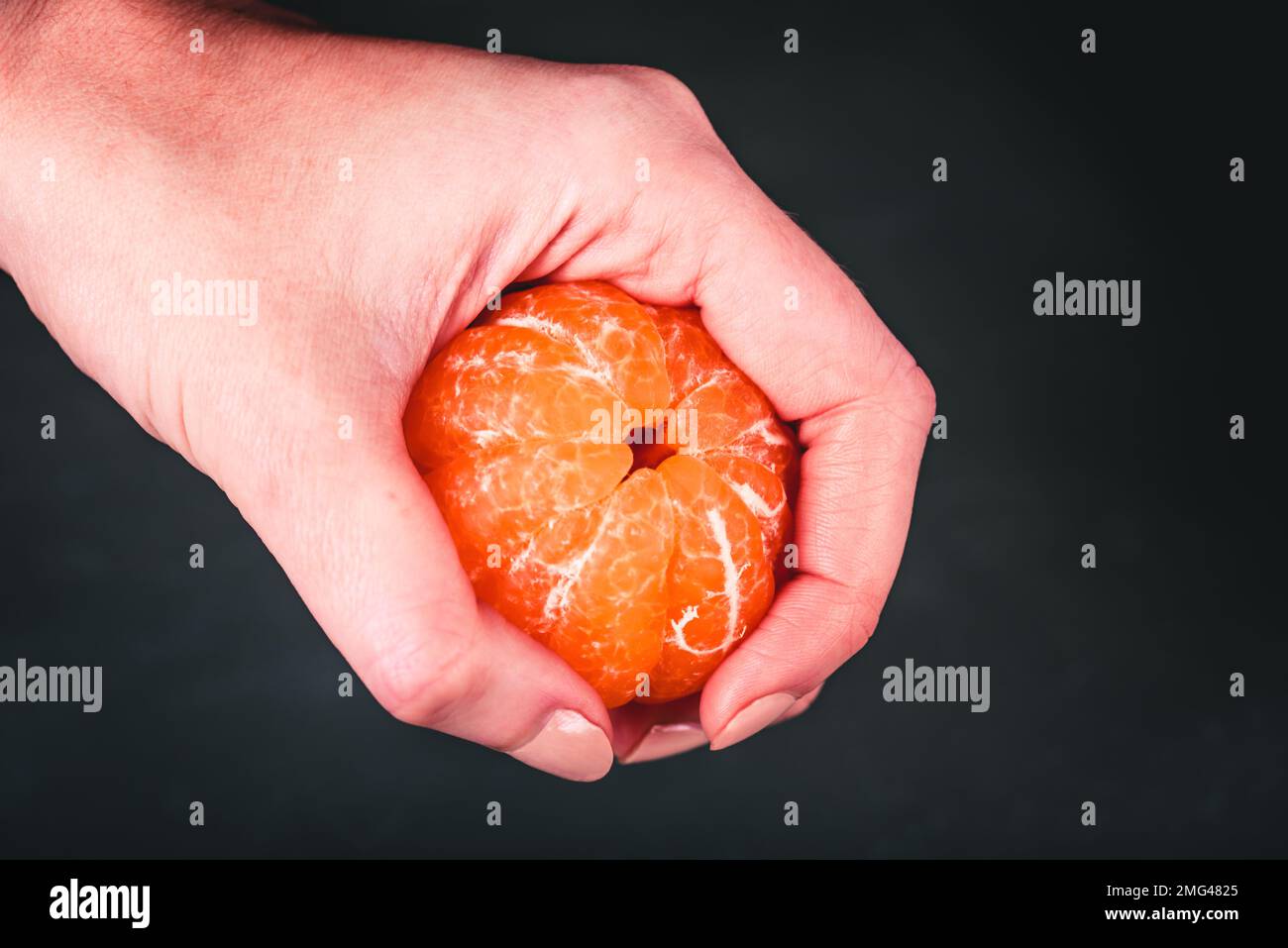 Frutta fresca. Un mandarino sbucciato in mano di donna. Foto Stock