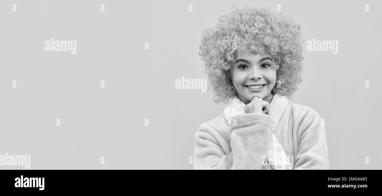 bambino allegro in fantasia arancio parrucca capelli indossare accappatoio a casa, mattina. Divertente bambino adolescente sulla festa, intestazione banner poster con spazio di copia. Foto Stock