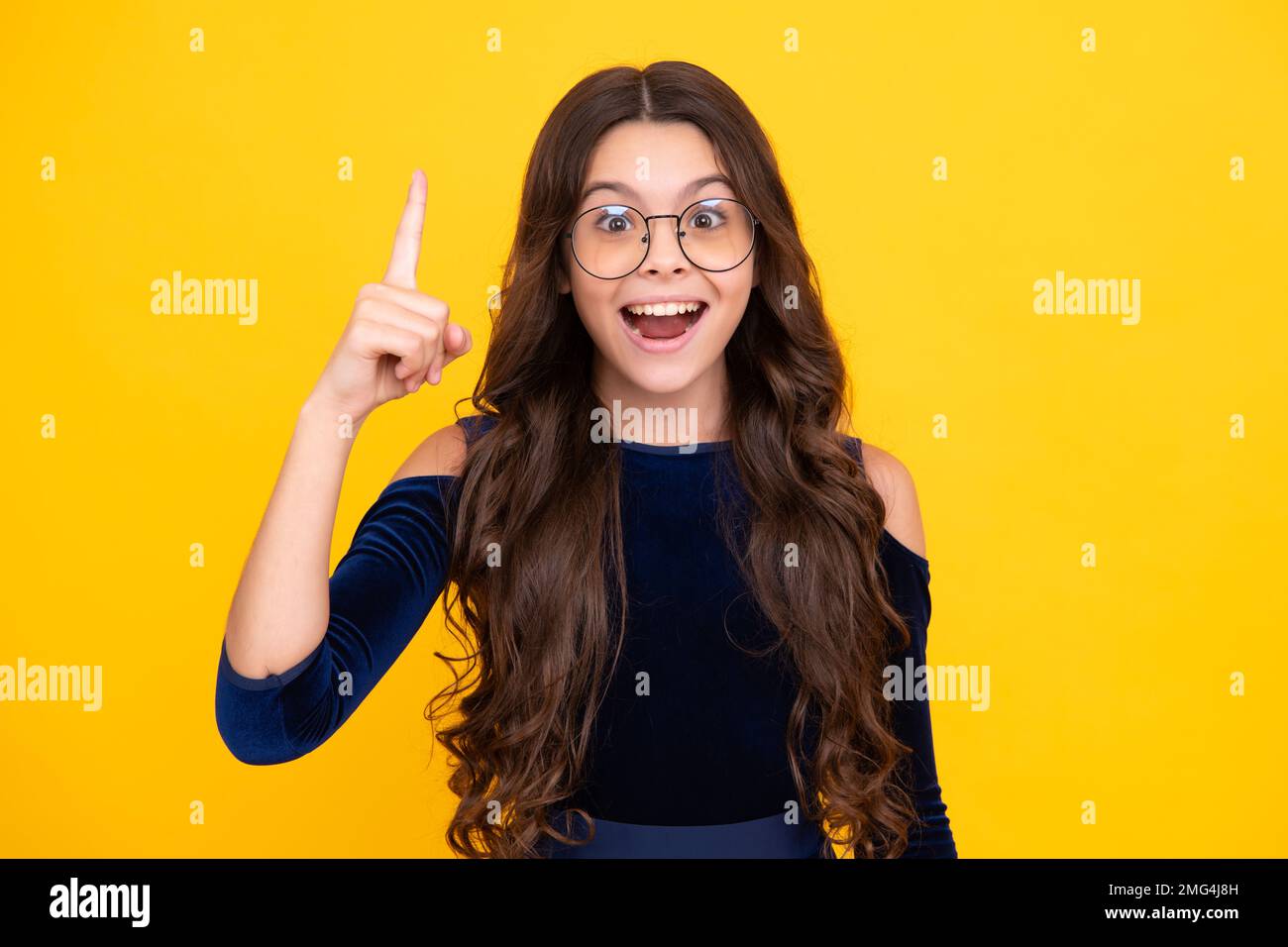 Ragazza giovane eccitata. Primo piano faccia divertente di giovane adolescente che punta con un dito, isolato su sfondo giallo. Ragazza ha grande nuova idea Foto Stock