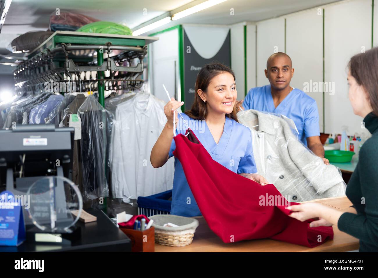 Donna addetto alla pulizia a secco che dona vestiti al cliente Foto Stock