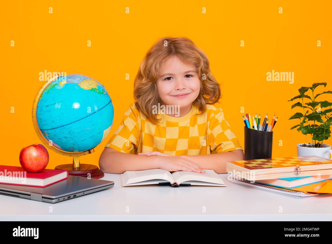 Allievo nerd della scuola elementare con libro isolato su sfondo giallo studio. Intelligenza geniale intelligente capretto pronto per imparare. Ritorno a scuola. Foto Stock