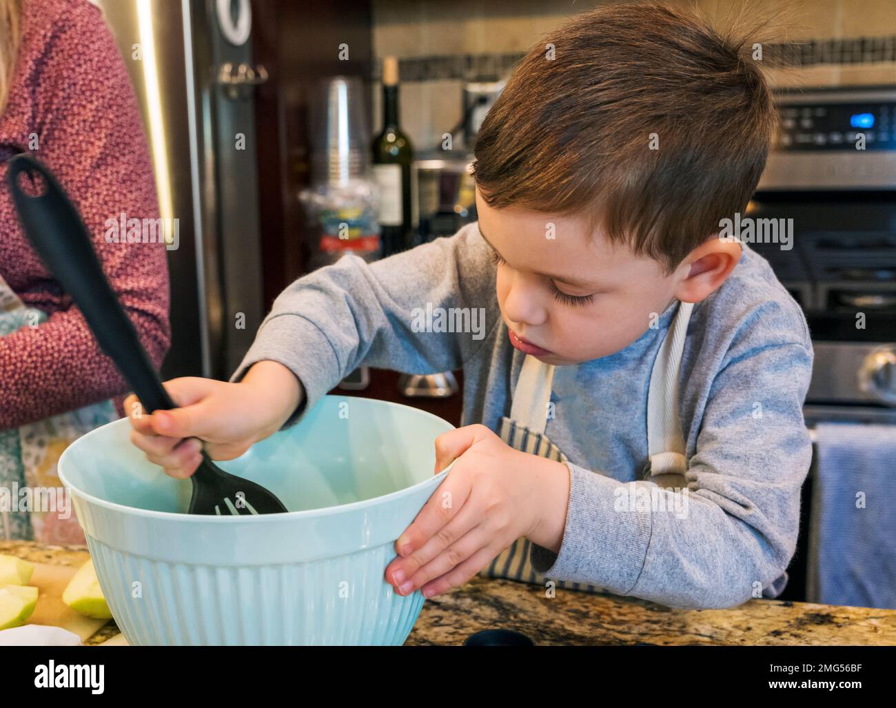 Bambino di tre anni che aiuta la nonna cuocere una torta di mele di festa di Thanksgiving; Philadelphia; Pennsylvania; USA Foto Stock
