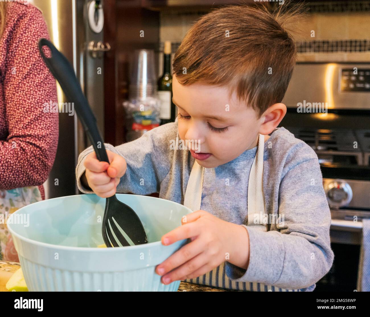 Bambino di tre anni che aiuta la nonna cuocere una torta di mele di festa di Thanksgiving; Philadelphia; Pennsylvania; USA Foto Stock