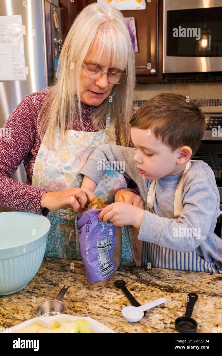 Bambino di tre anni che aiuta la nonna cuocere una torta di mele di festa di Thanksgiving; Philadelphia; Pennsylvania; USA Foto Stock