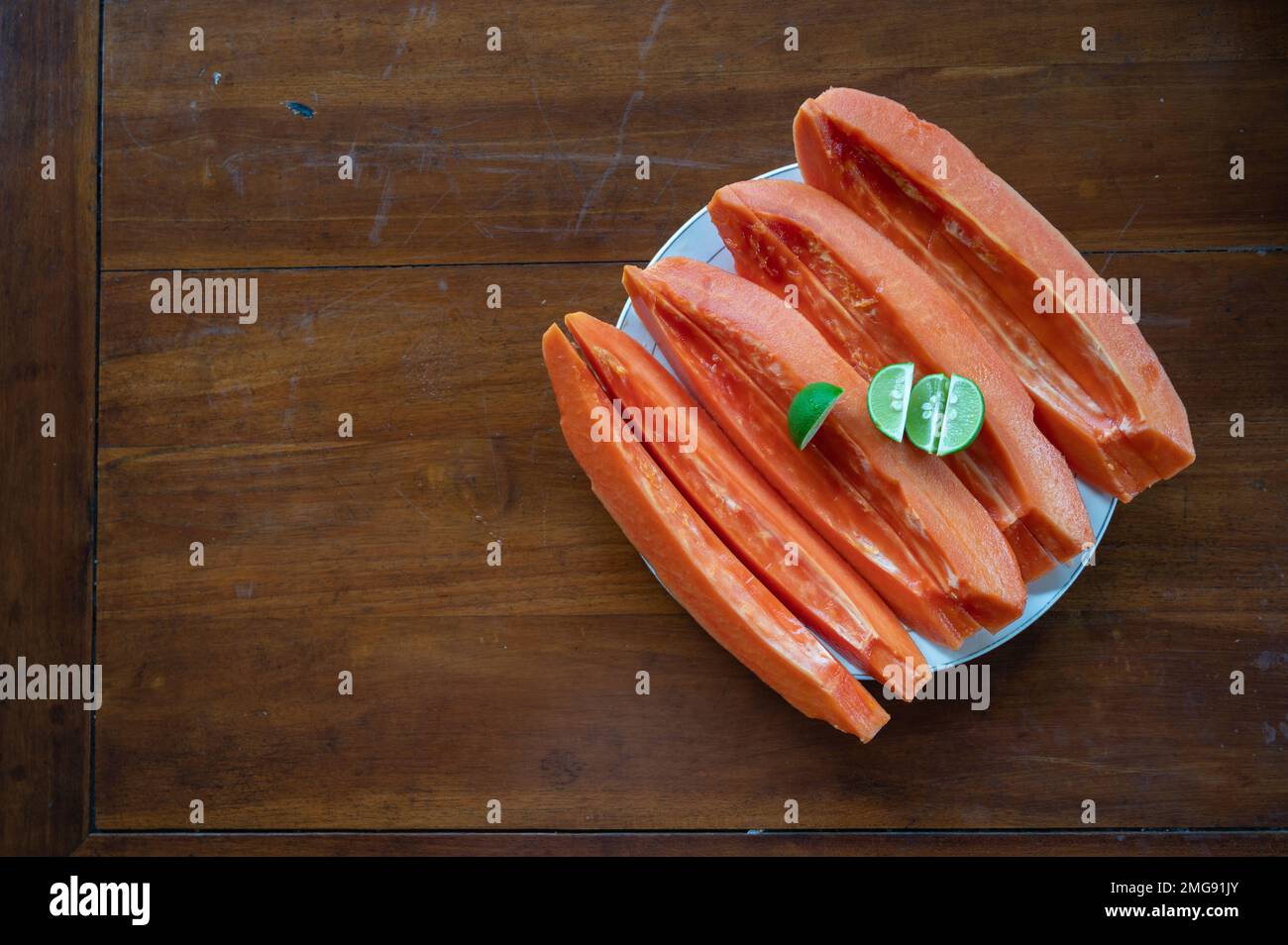 Papaya a fette con lime sul tavolo vicino alla piscina Foto Stock