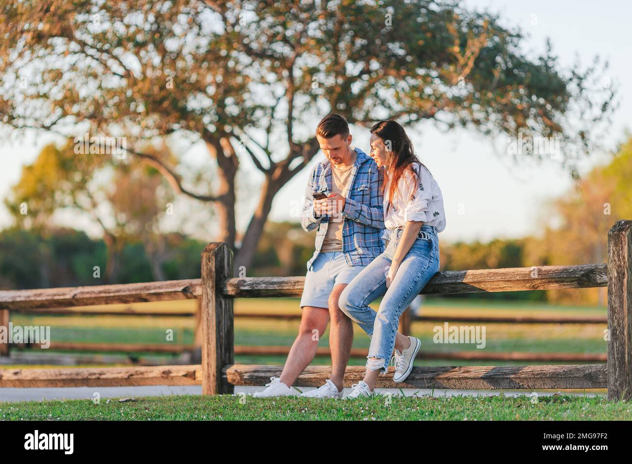 Famiglia di due persone nel parco il giorno d'estate con smartphone Foto Stock