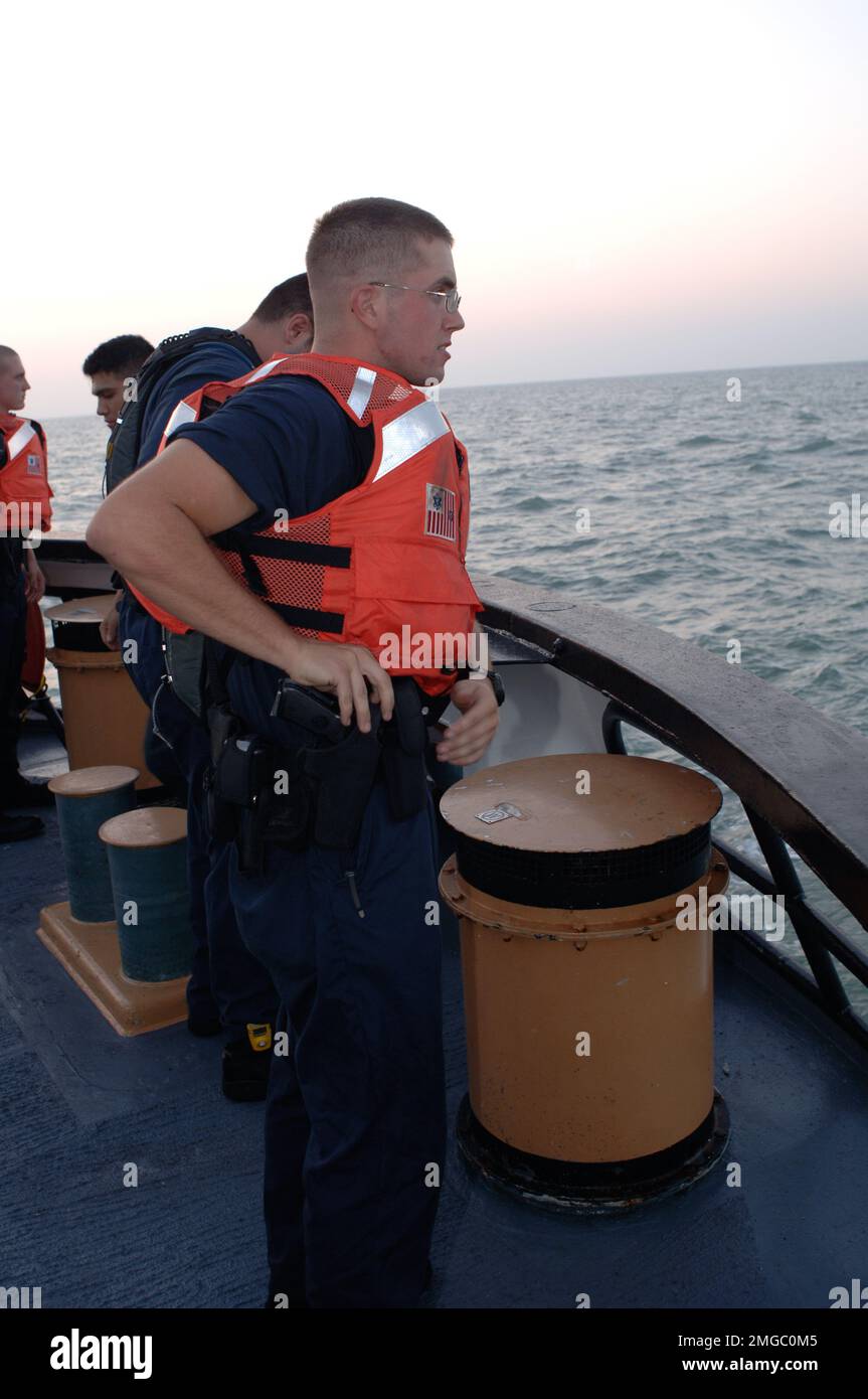Taglierine per cofani - senza raccordo (WMEC 624) - 26-HK-73-46. CGC Dauntless -- Coast Guardsman che restituisce la pistola alla custodia mentre mannando le rotaie --050928. Uragano Katrina Foto Stock