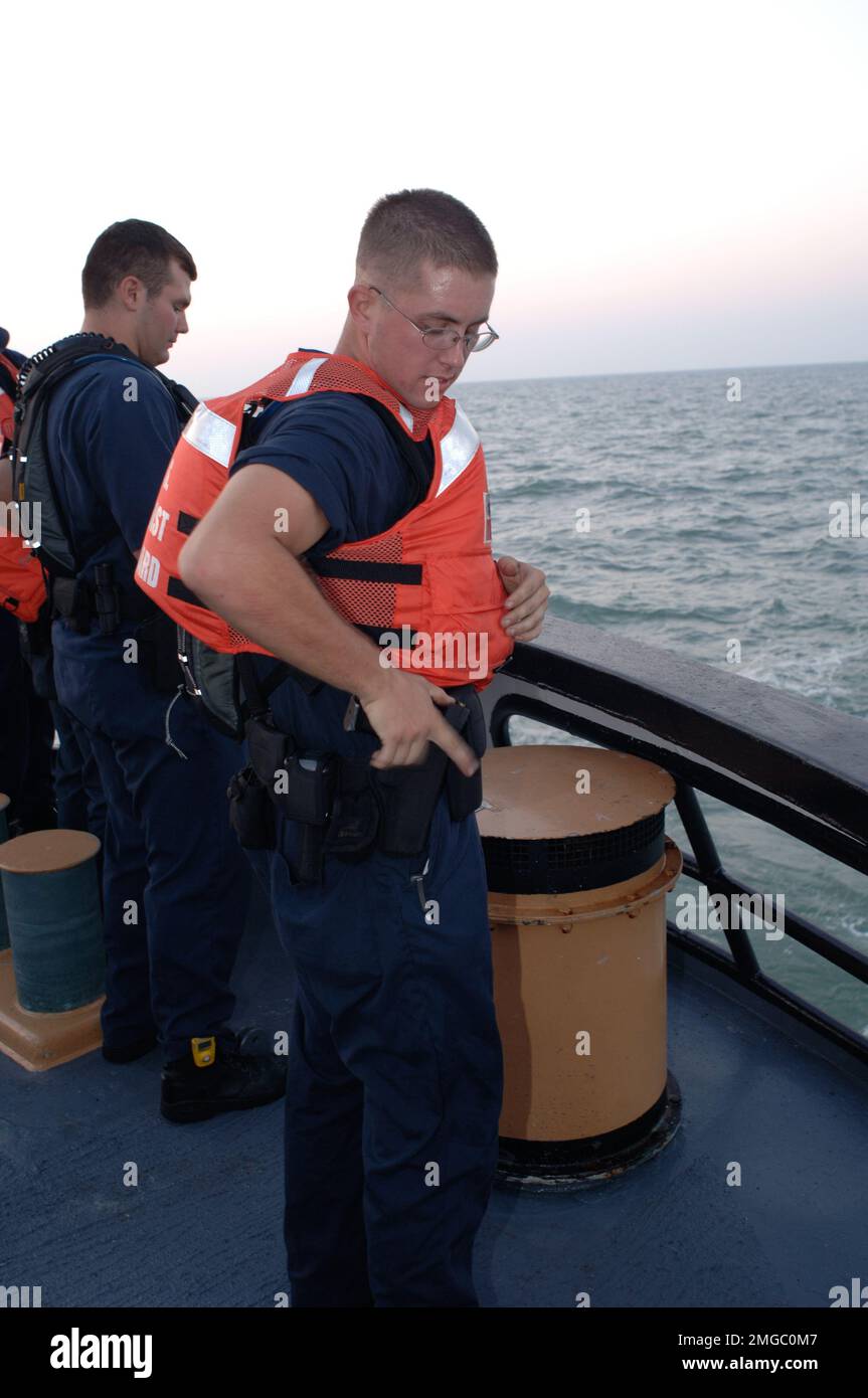 Taglierine per cofani - senza raccordo (WMEC 624) - 26-HK-73-177. CGC Dauntless --Coast Guardsman di ritorno pistola alla custodia mentre manning binari--050928. Uragano Katrina Foto Stock