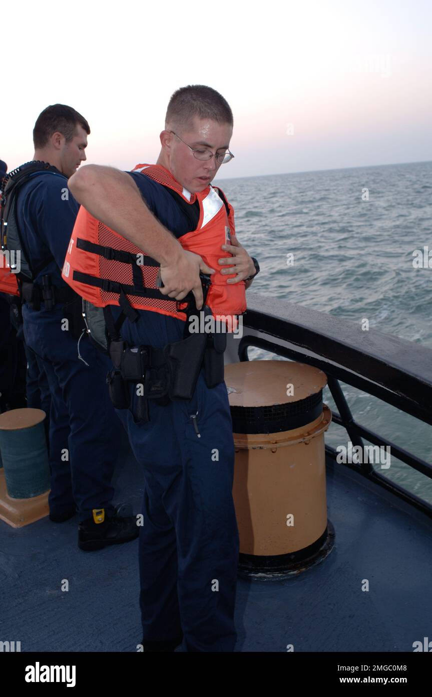 Taglierine per cofani - senza raccordo (WMEC 624) - 26-HK-73-47. CGC Dauntless -- Coast Guardsman che restituisce la pistola alla custodia mentre mannando le rotaie --050928. Uragano Katrina Foto Stock