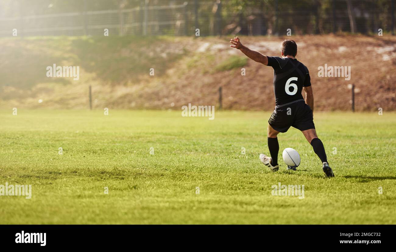 Rugby, giocatore e calci una palla sportiva su un campo durante la pratica, l'esercizio fisico o l'allenamento all'aperto. Atleta, sportivo e uomo durante una partita che prende un Foto Stock