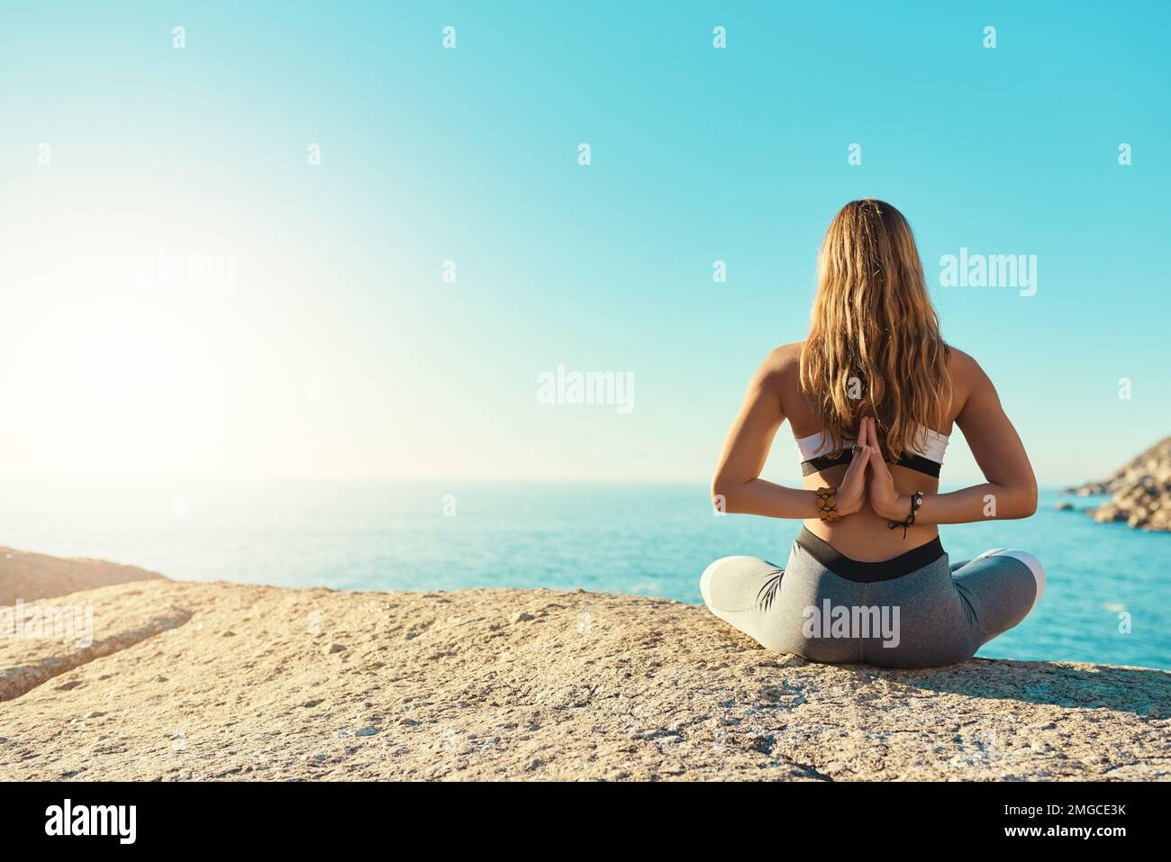 Vai a trovarti. Ripresa da dietro di una giovane donna che pratica yoga sulla spiaggia. Foto Stock