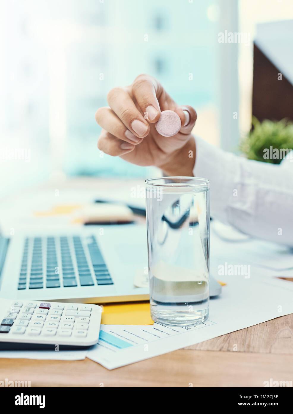 Sciogliere e bere. un uomo d'affari irriconoscibile che scioglie una compressa effervescente in un bicchiere d'acqua. Foto Stock