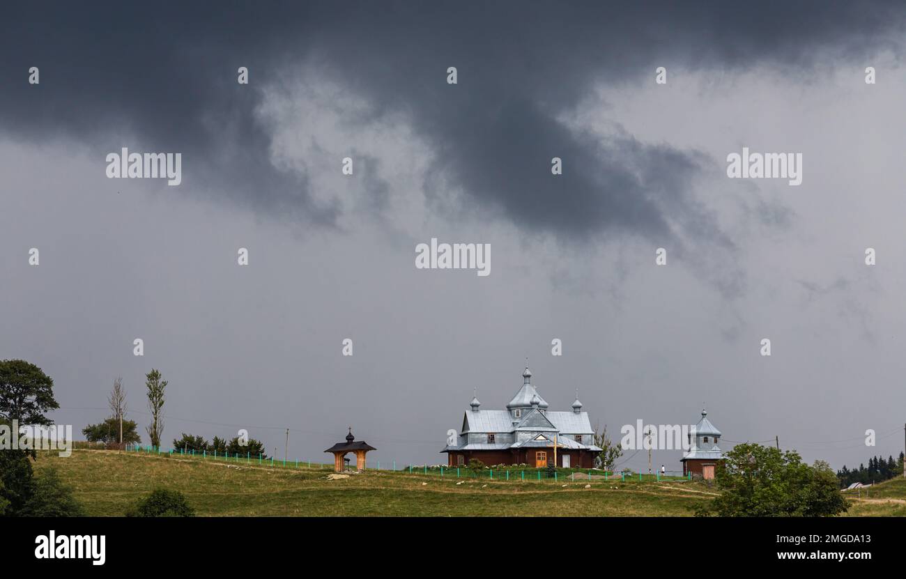 Nuvole tempesta, cielo minaccioso, collina e chiesa, alberi verdi prima della pioggia. Foto Stock