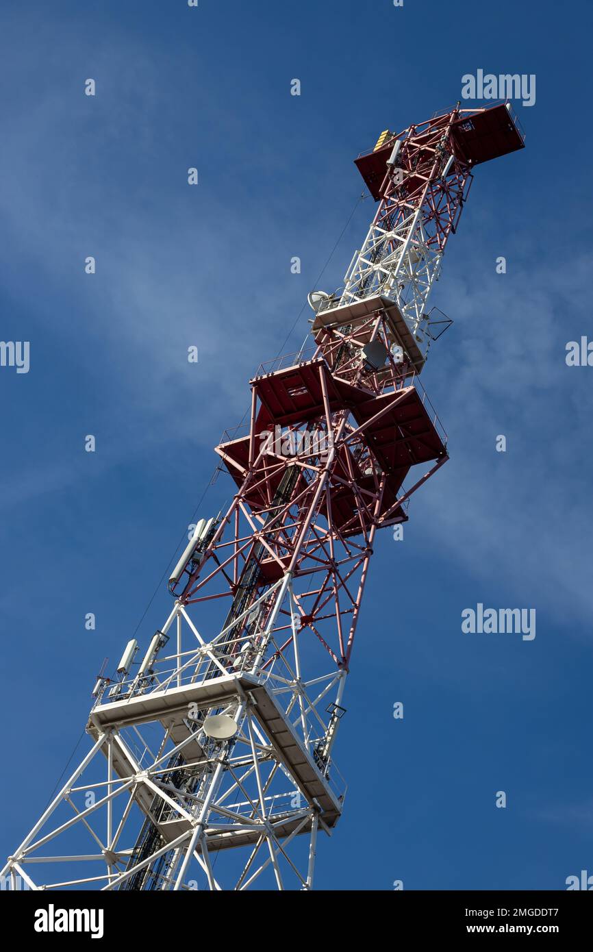 Antenna per telecomunicazioni per radio, televisione e telefonia con nuvola e cielo blu. Foto Stock