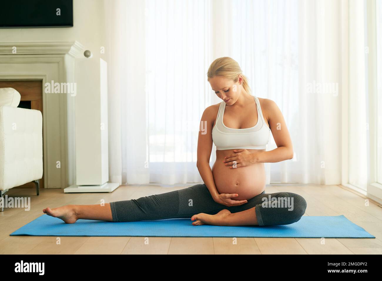 Il suo corpo può cambiare, ma le sue scelte di stile di vita non hanno. una donna incinta che fa yoga su un tappetino per l'esercizio fisico a casa. Foto Stock