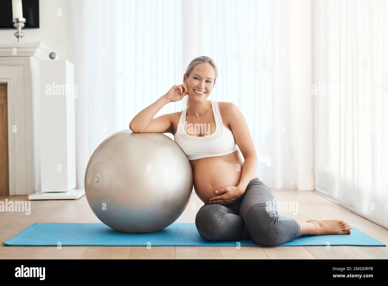 Niente come un po' di esercizio leggero per sollevare gli spiriti. una donna incinta che si alleni con una palla da ginnastica a casa. Foto Stock