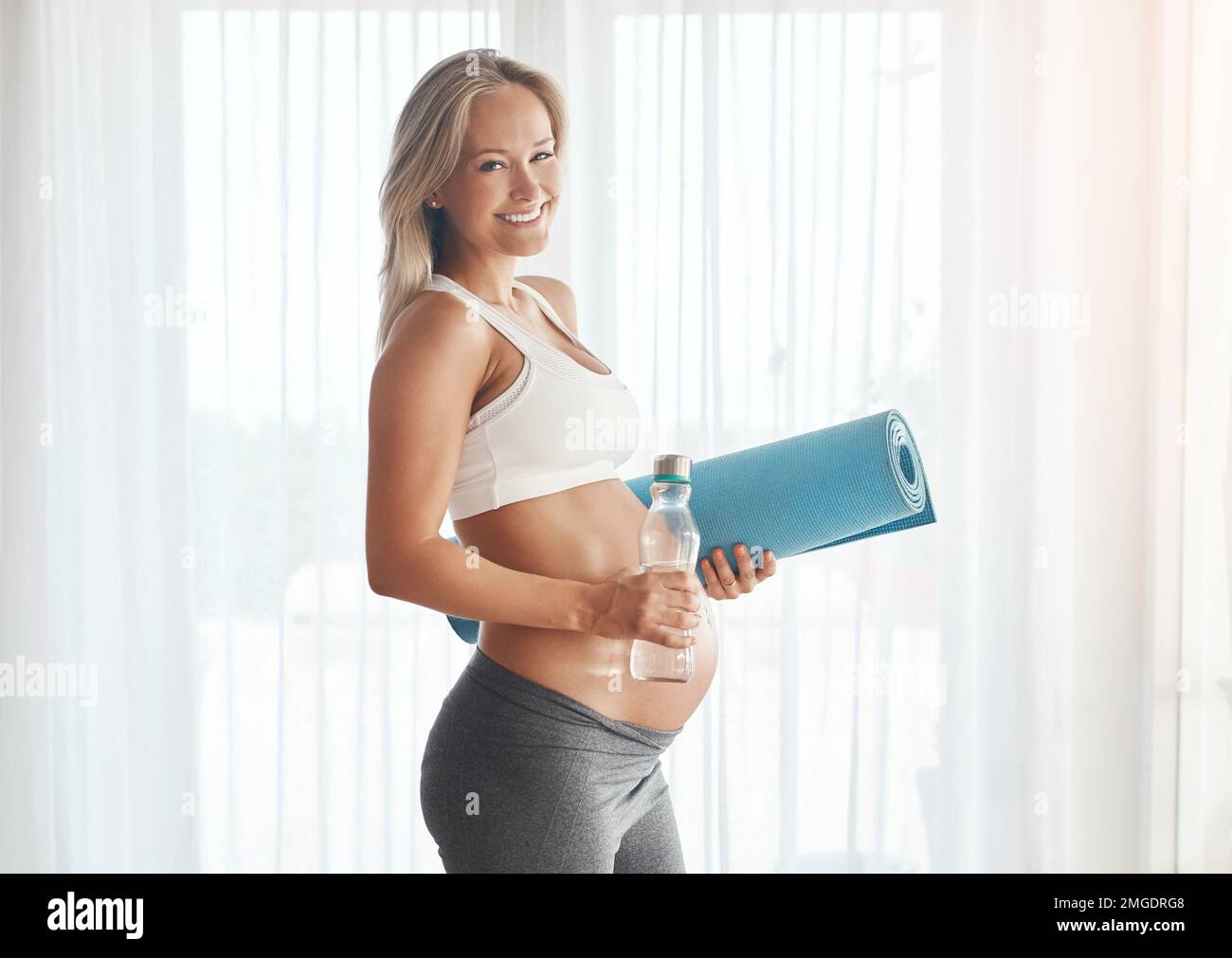 Crescere un bambino sano con uno stile di vita sano. Ritratto di una donna incinta felice che si prepara ad allenarsi a casa. Foto Stock