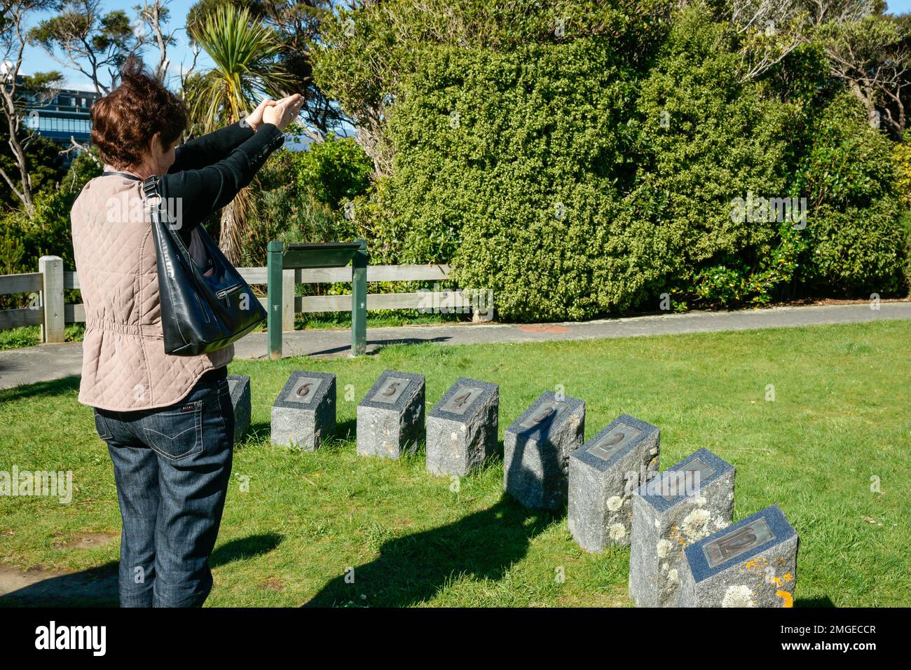 Wellington Nuova Zelanda - 2 2010 ottobre; turista con le armi sollevate che gettano un'ombra di tempo al Dial del Sole di coinvolgimento umano nei Giardini Botanici Foto Stock
