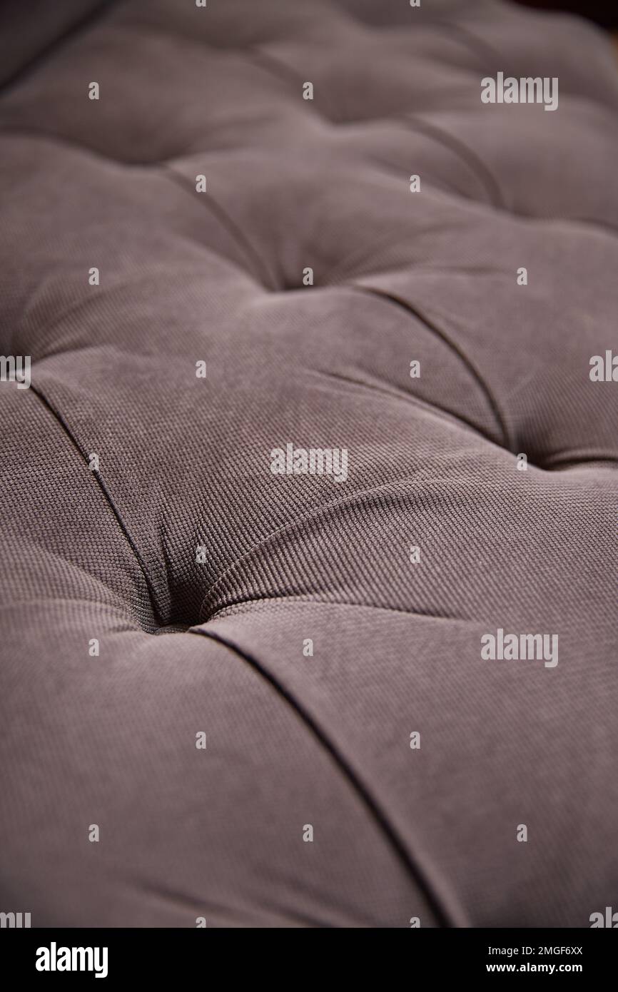 Tappezzeria grigia di un divano molto morbido con bottoni in tessuto spesso. Primo piano Foto Stock