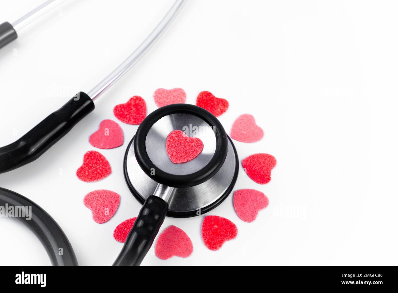 Primo piano stetoscopio ascoltando il cuore rosa e rosso su uno sfondo bianco con spazio di copia. Medico che ama la medicina, le malattie cardiache e la cardiologia. Foto Stock