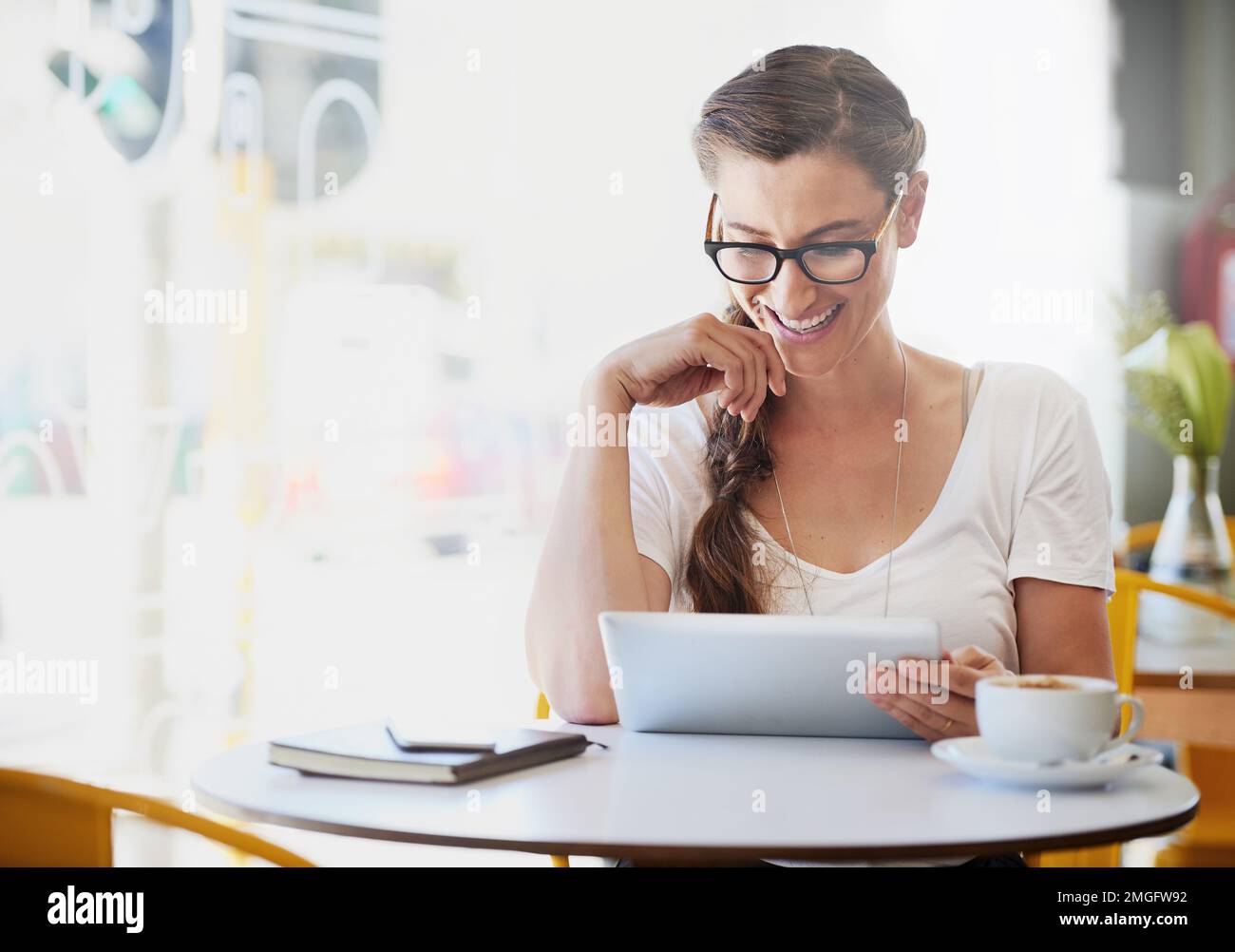 Vieni a bere un caffè e a utilizzare il wifi. una giovane donna rilassata che usa la sua tavoletta mentre beve caffè nel suo caffè preferito. Foto Stock