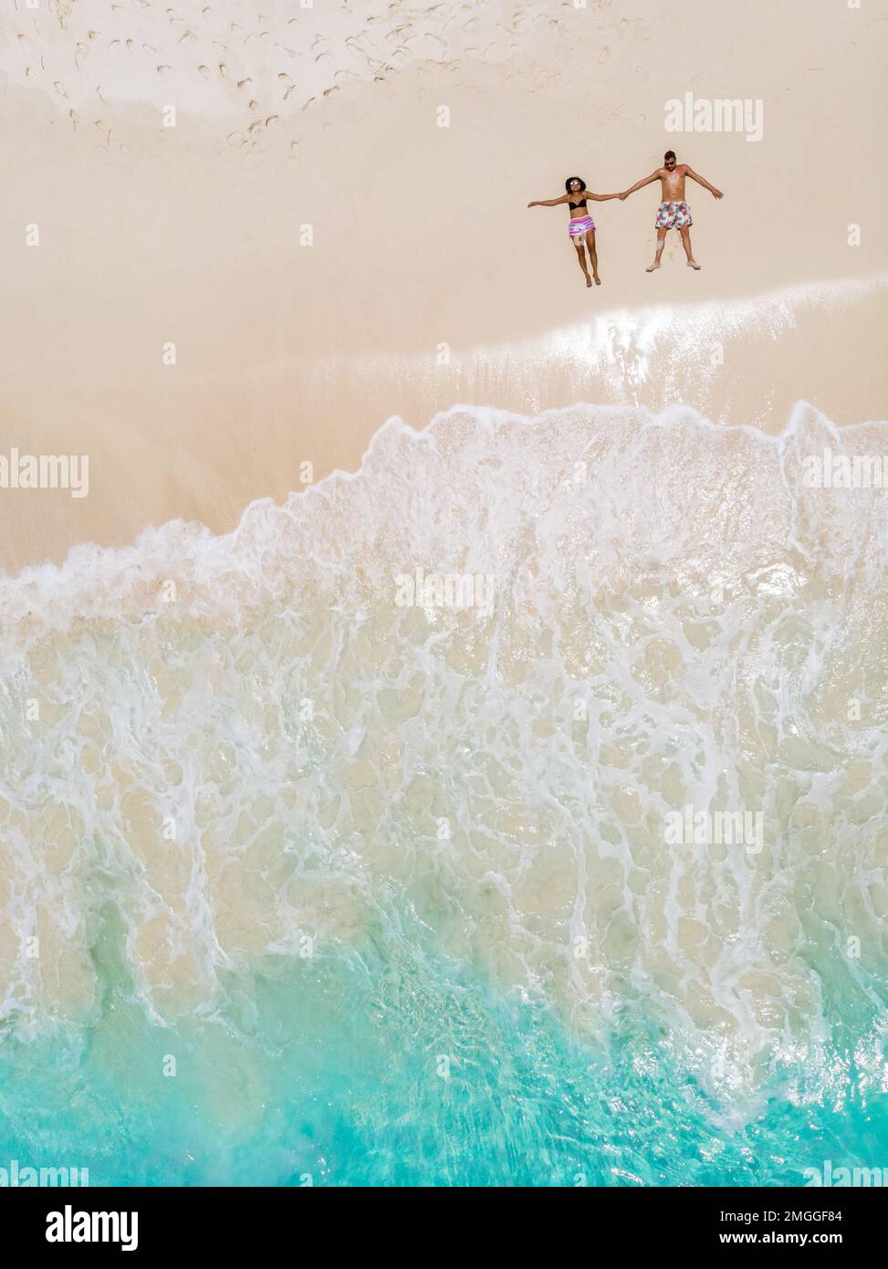 Uomo e donna che si adagia su una spiaggia tropicale, vista drone dall'alto su una spiaggia tropicale nell'Isola di Cocos Seychelles Foto Stock