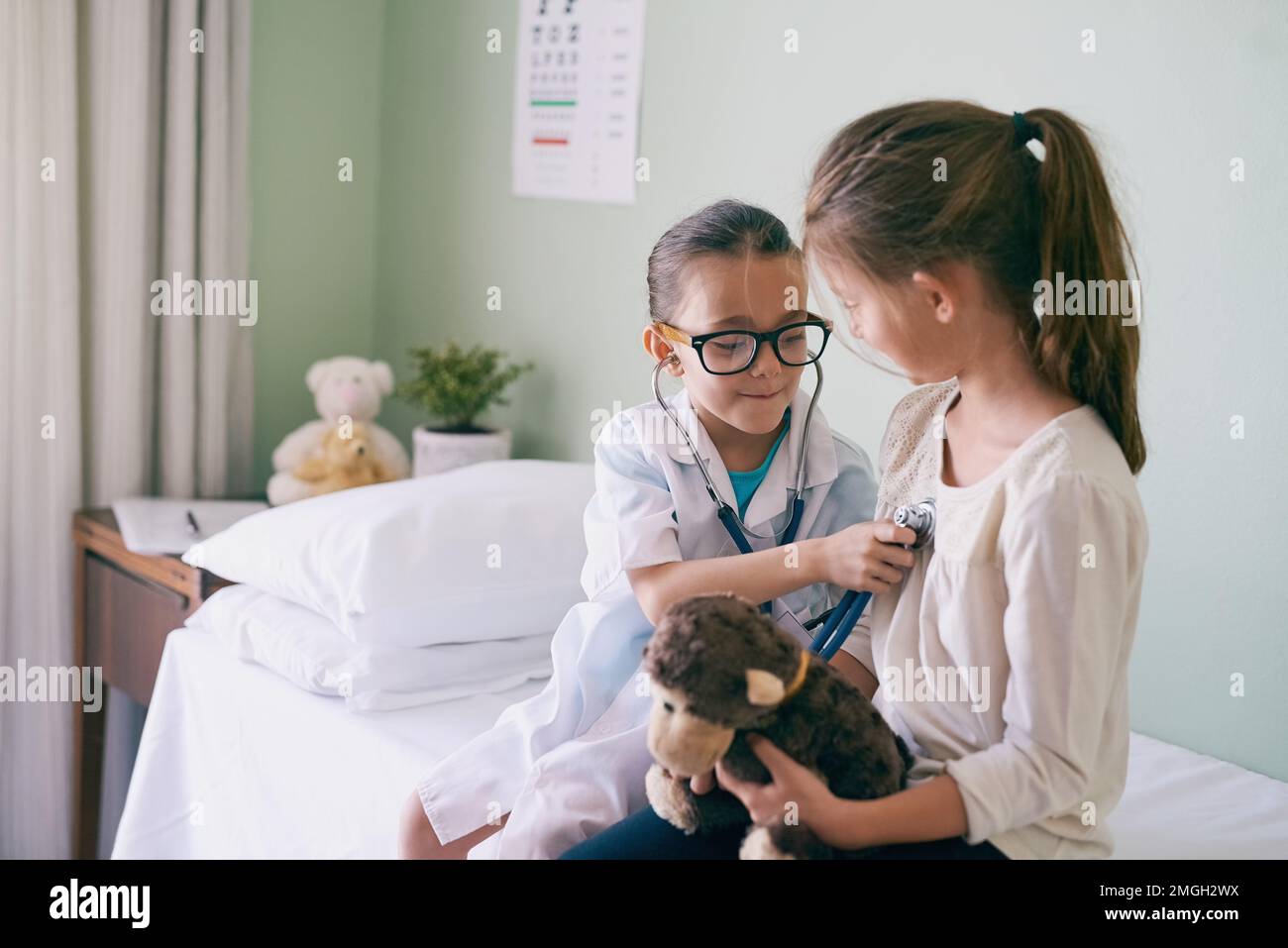 Penso che il tuo cuore abbia bisogno di più tempo di gioco con me. una bambina che finge di essere un medico mentre esamina la sua amica. Foto Stock