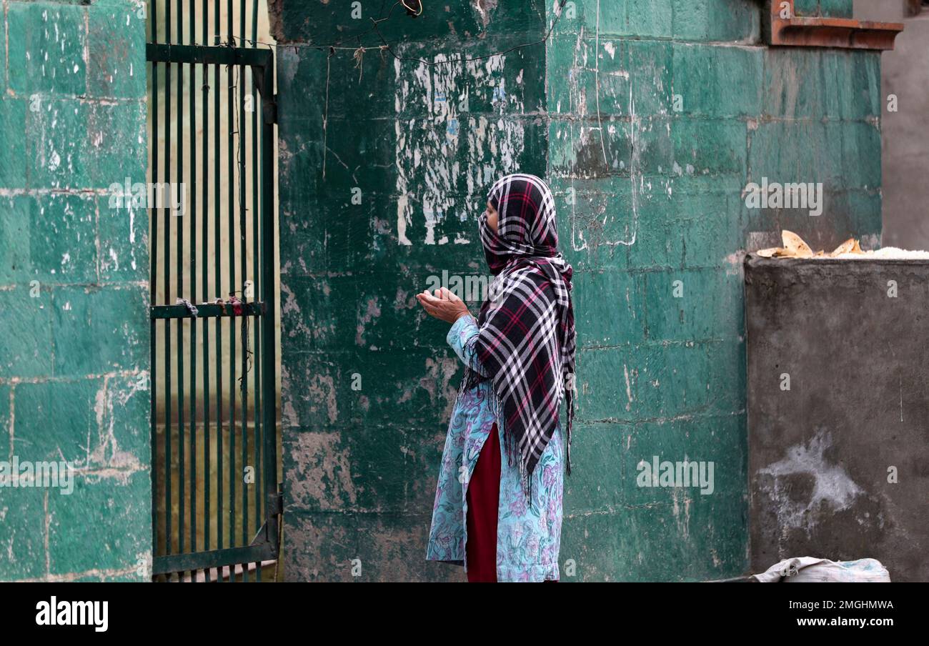 A Kashmiri Muslim woman prays outside the closed gate of a Muslim shrine on the second day of Ramadan during lockdown to prevent the spread of the new coronavirus in Srinagar, Indian controlled Kashmir, Sunday, April 26, 2020. Kashmiri shrines that are usually packed with devotees during the holy month of Ramadan wore a deserted look Sunday as authorities closed the shrine for the safety of the public. (AP Photo/Mukhtar Khan) Foto Stock