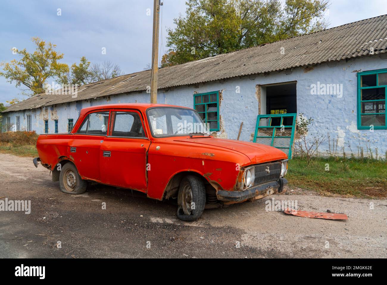 Auto civile distrutta si trova vicino a una casa distrutta. Sul corpo della vettura ci sono buchi da proiettili e schegge. Invasione russa dell'Ucraina Foto Stock