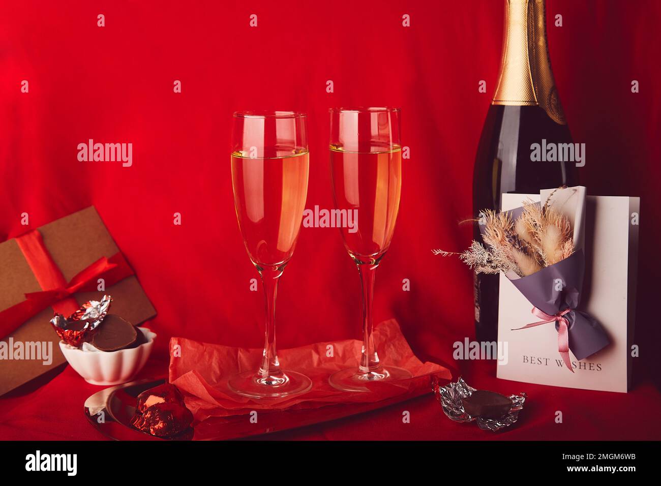 Estetica San Valentino sfondo. Cena romantica di stagione rossa con omaggio, cartolina, champagne e caramelle al cioccolato. Foto Stock
