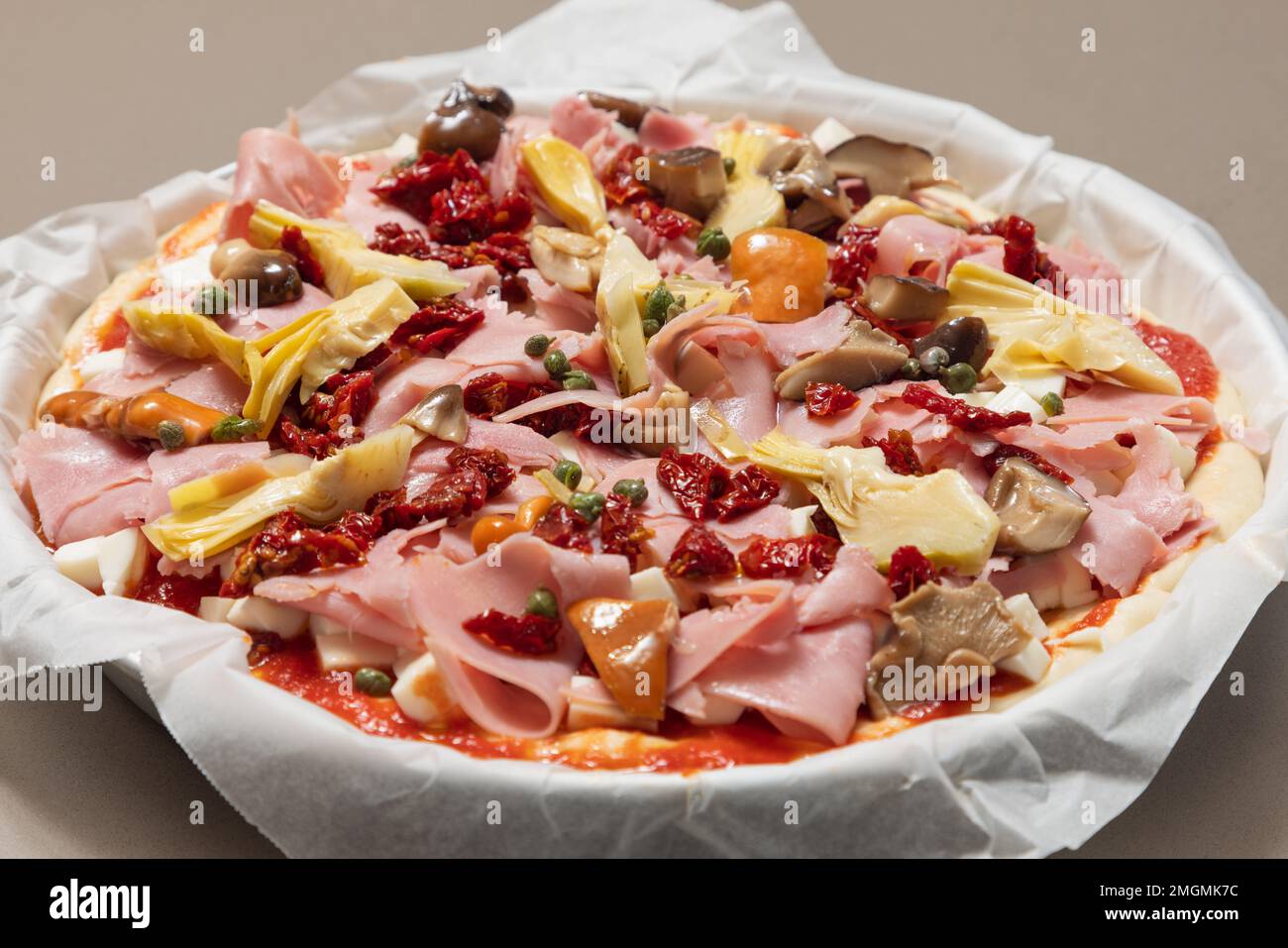 Pizza capricciosa italiana cruda fatta in casa con ingredienti classici pronti per la cottura (focus selettivo) Foto Stock