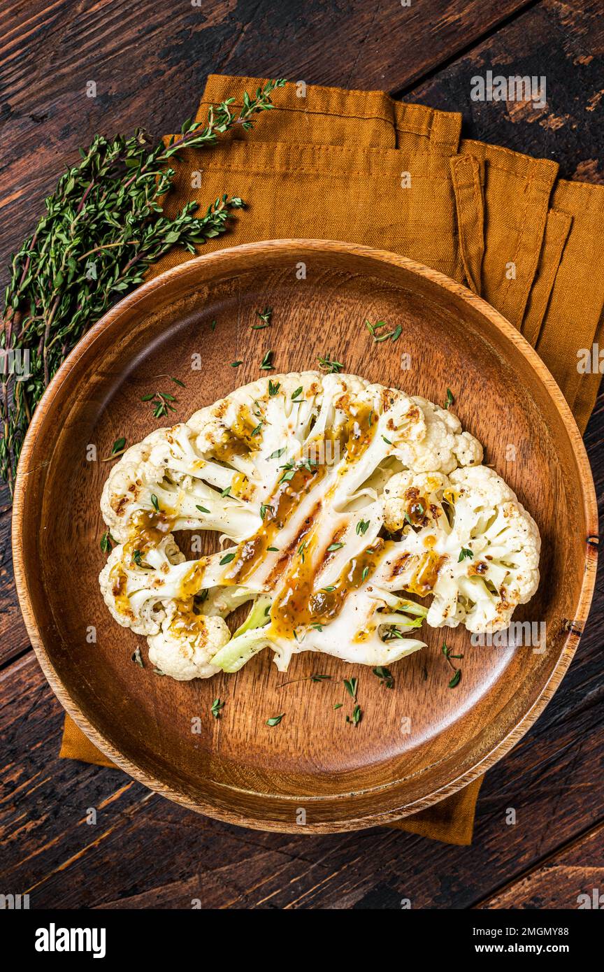 Bistecche di cavolfiore alla griglia con salsa al cilantro al cime chimichurri, carne a base di piante. Sfondo di legno. Vista dall'alto Foto Stock