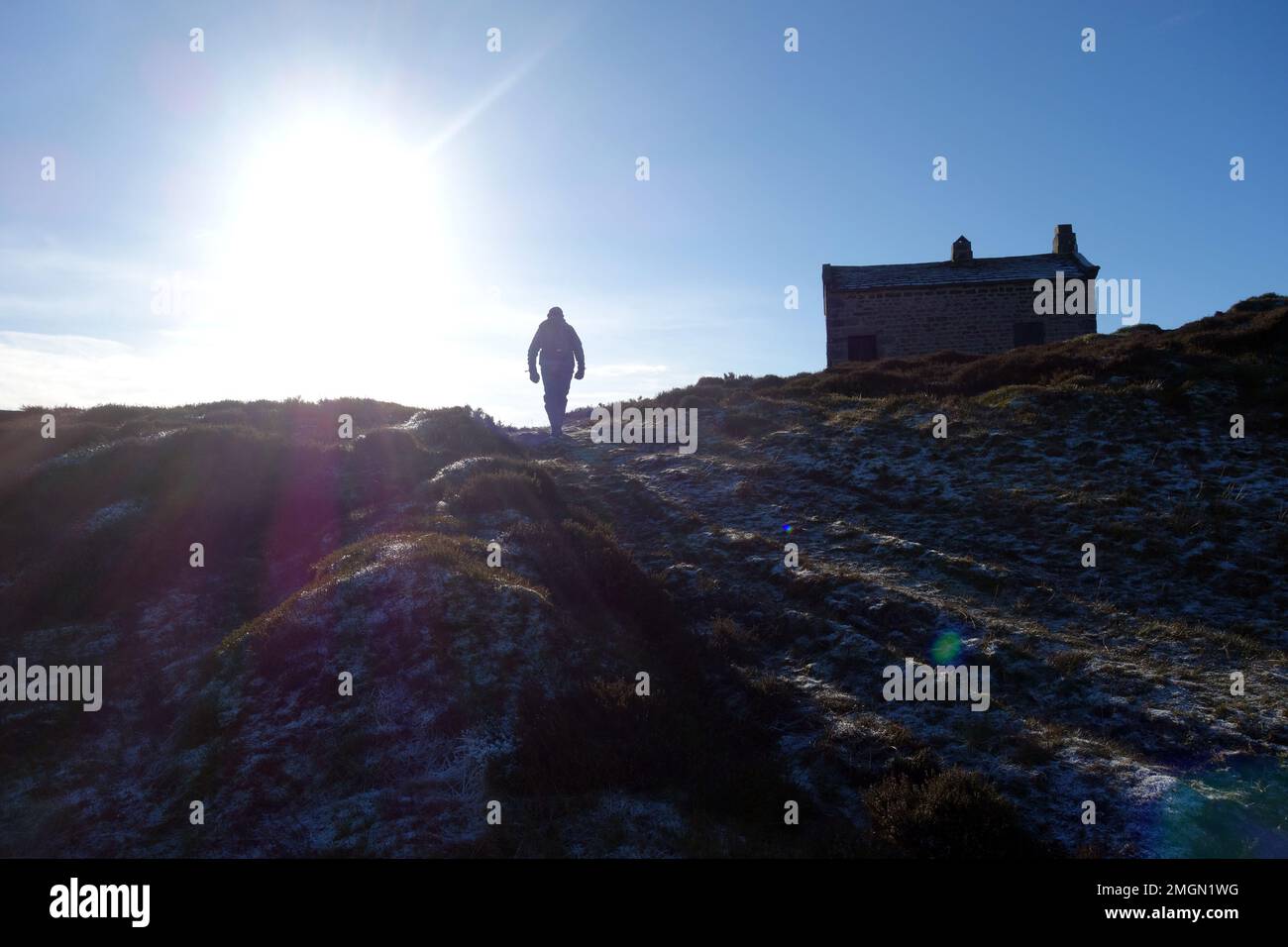 Man Walking in Track into the Sunset by the Shooting Hut to the Summit of 'Cracoe Fell' on Barden Moor nel Yorkshire Dales National Park, England. Foto Stock