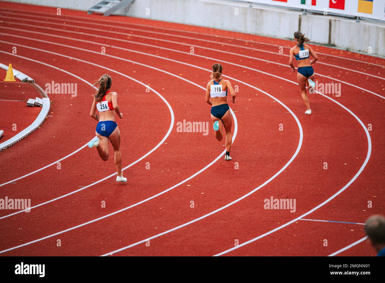 Le atlete alla linea di partenza di una gara 400m in pista, mostrando la loro attenzione e determinazione mentre si preparano a competere Foto Stock