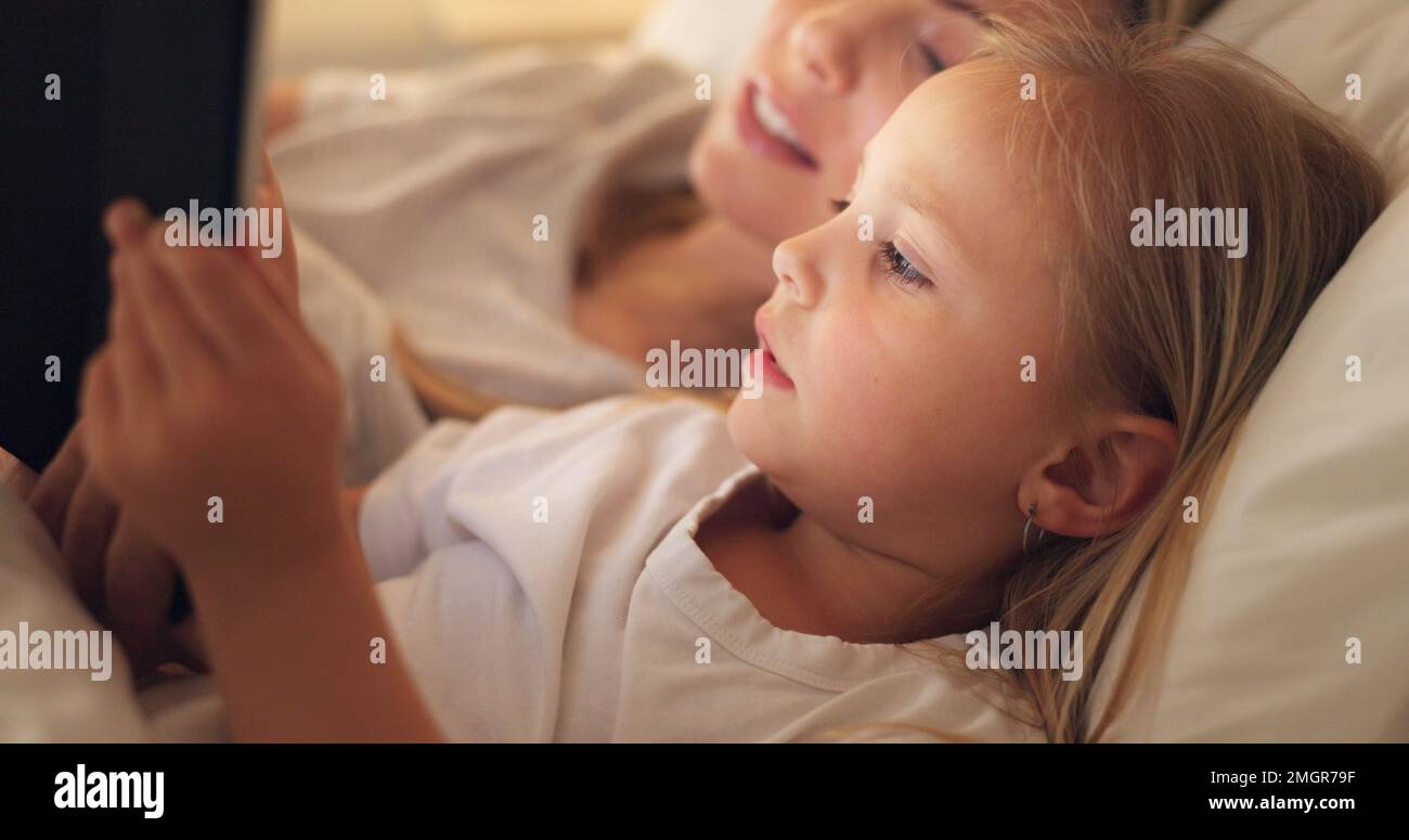 Tablet, madre e bambino su Internet a letto, streaming di un film o lettura di un libro sul web di notte. Istruzione, apprendimento e giochi sulla tecnologia Foto Stock