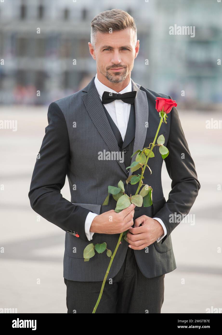 elegante uomo in smoking per un'occasione romantica. uomo con un regalo  romantico. uomo romantico con rosa Foto stock - Alamy