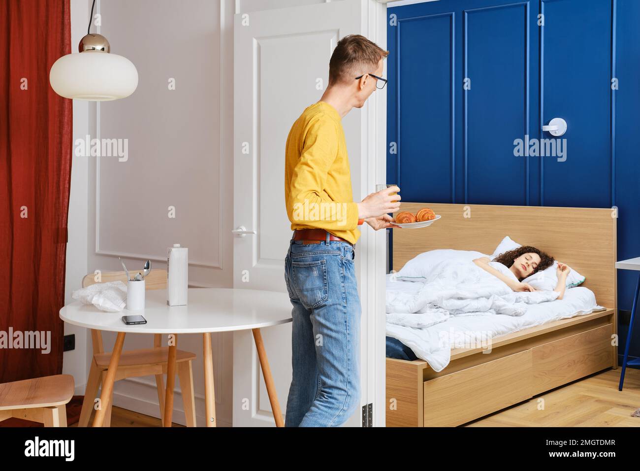 L'uomo porta la colazione a letto alla moglie che dorme Foto Stock