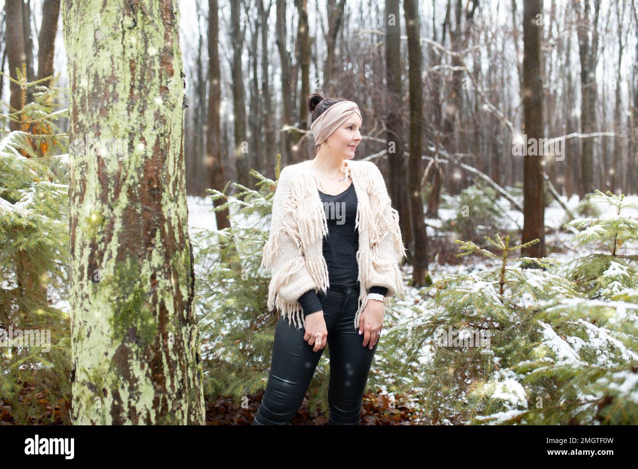 Donna felice nella foresta d'inverno. Ritratto femminile in parco di neve. Donna con archetto in posizione accogliente e guardare lontano. Foto Stock