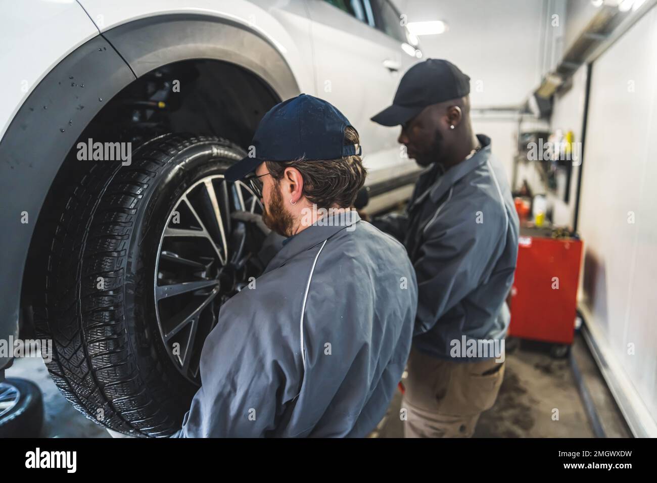 I meccanici dell'automobile sostituiscono le ruote di un'automobile sollevata in una stazione di servizio di riparazione. Foto di alta qualità Foto Stock