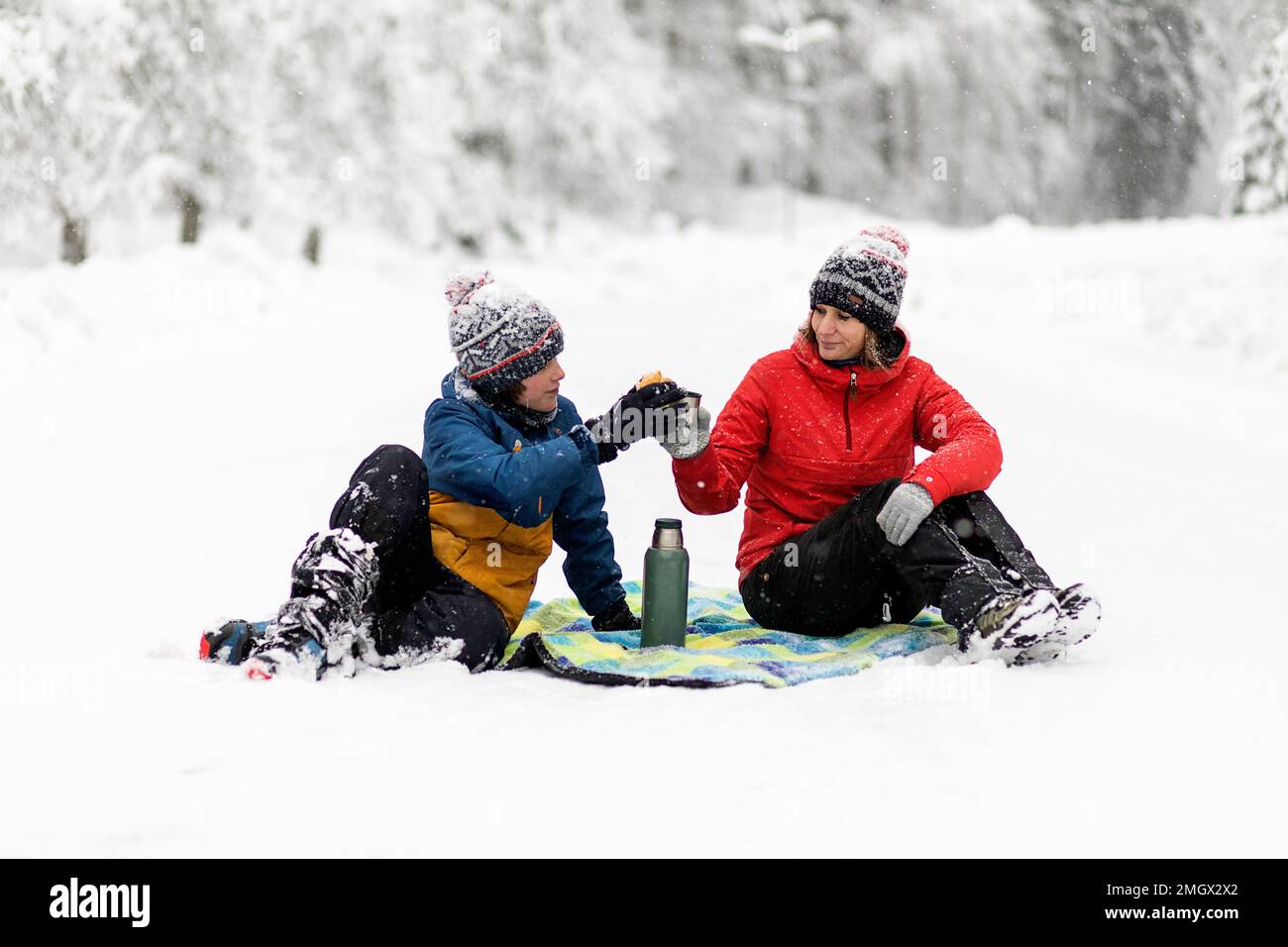 Madre e figlio hanno un picnic invernale in nevicata nelle foreste primordiali della regione di Notranjska, a Kocevski rog, Slovenia Foto Stock