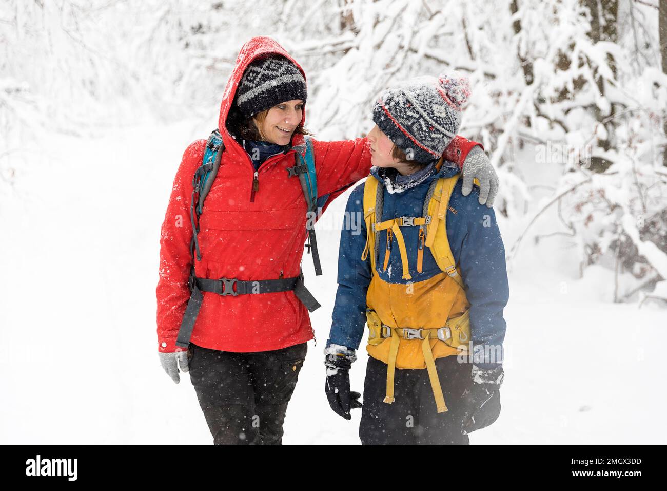Madre e figlio si divertono mentre camminano in inverno durante le nevicate nelle foreste primordiali della regione di Notranjska, Dolenjske toplice, Slovenia Foto Stock