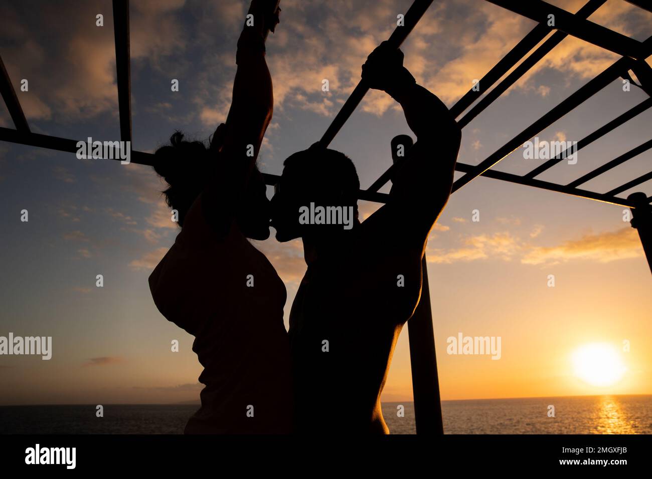 Silhouette di due atleti innamorati che baciano durante l'allenamento al tramonto Foto Stock