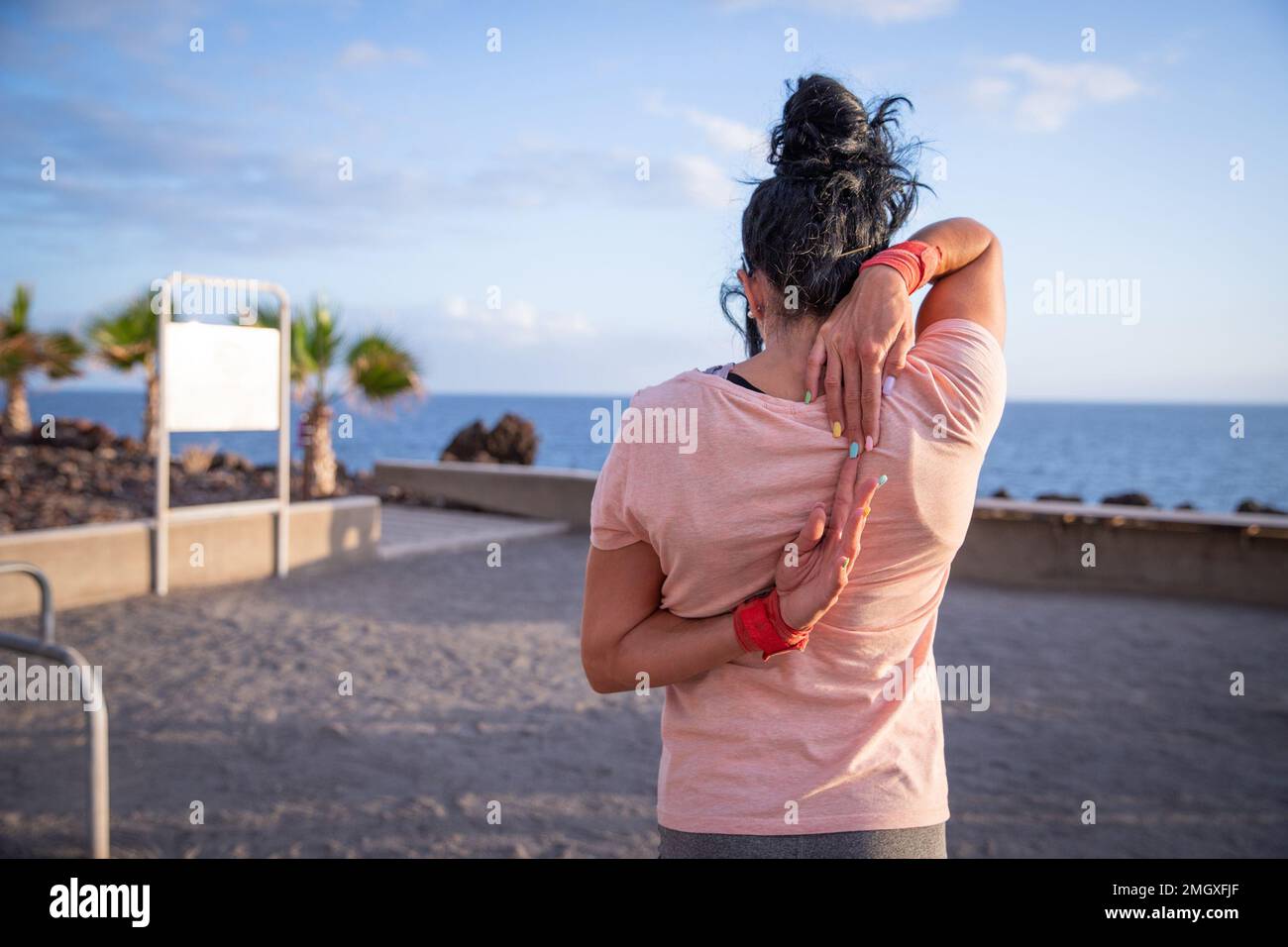Una donna si allunga e tocca le mani dietro la schiena, foto con spazio copia a sinistra Foto Stock