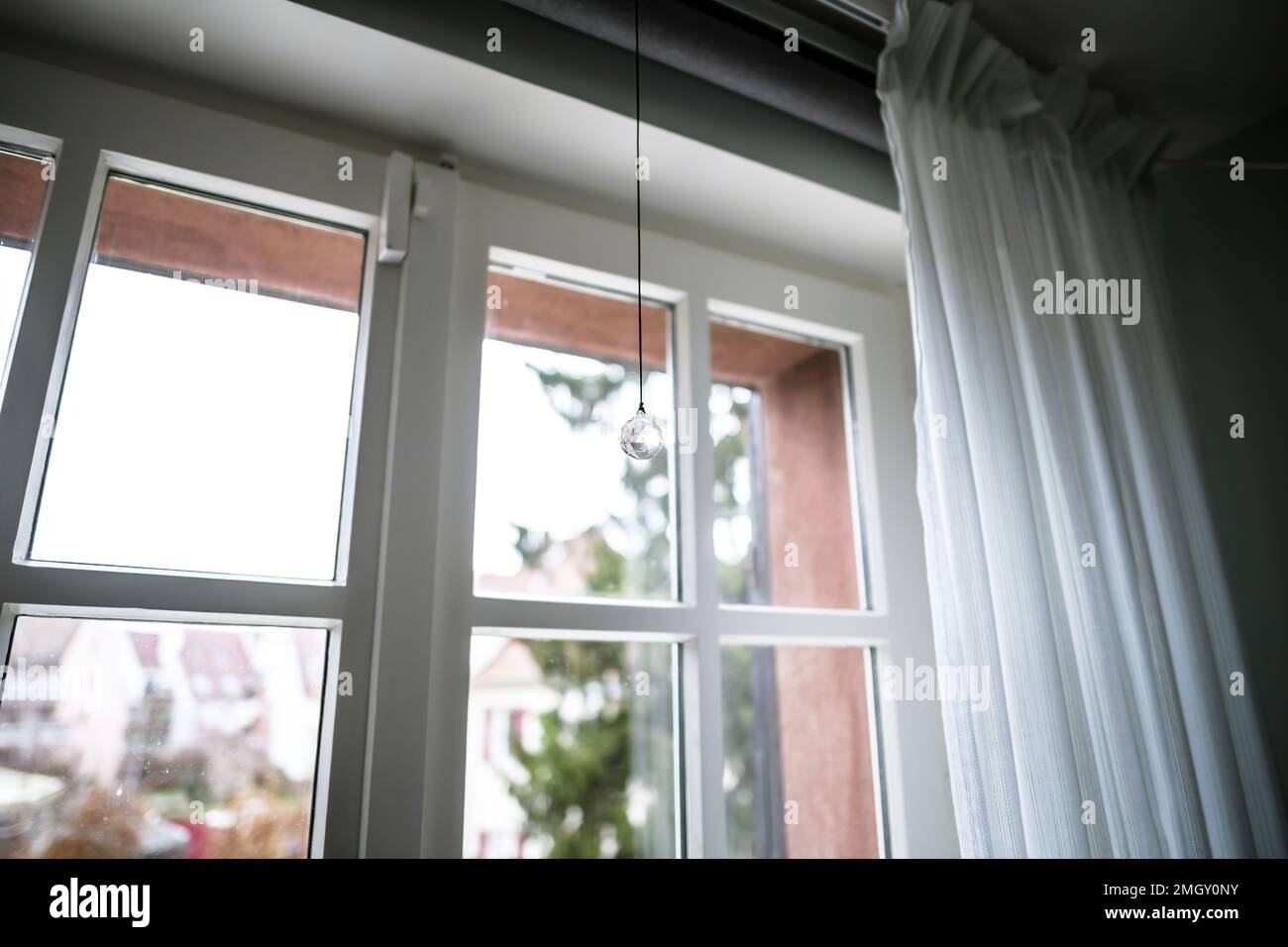 Vista dal basso angolo del Suncatcher del produttore di arcobaleno di cristallo appeso vicino alla finestra in una giornata di pioggia Foto Stock