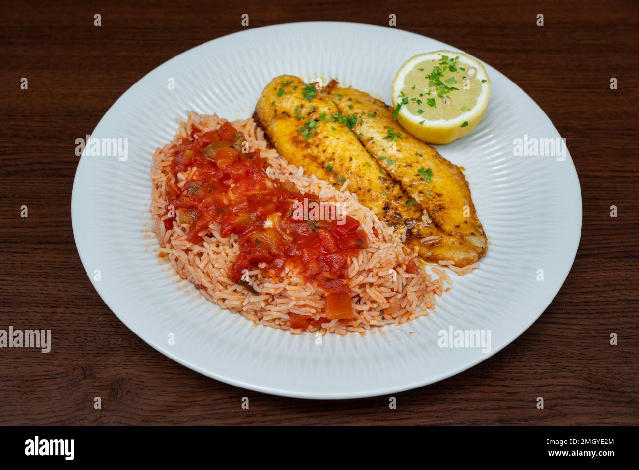 Filetto di pesce fritto fresco guarnito con riso in salsa di pomodoro ed erbe aromatiche. Foto Stock