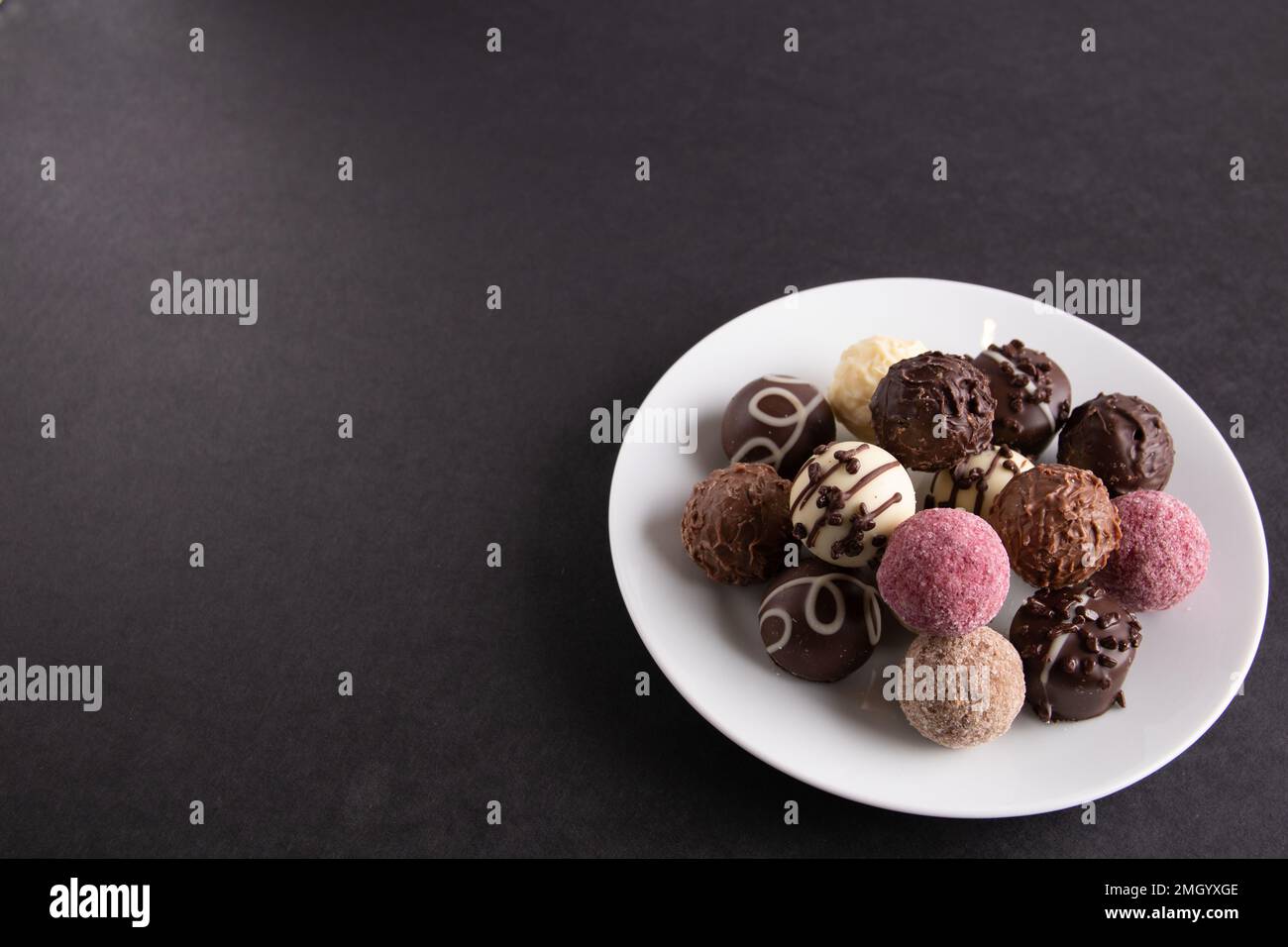 foto su un piatto ci sono cioccolatini su uno sfondo nero Foto Stock