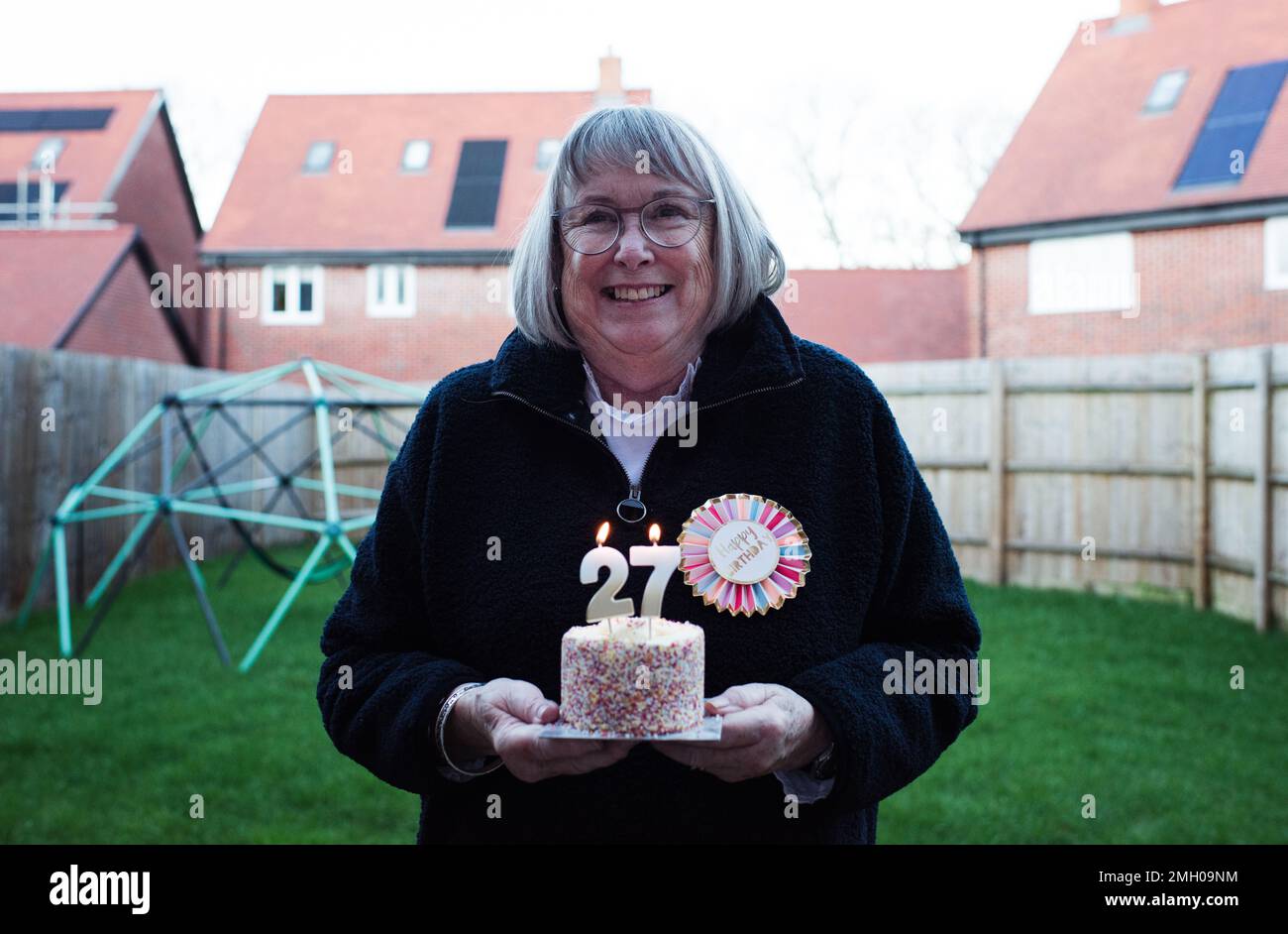 lady festeggia felicemente il suo 72nd° compleanno con torta e candele Foto Stock