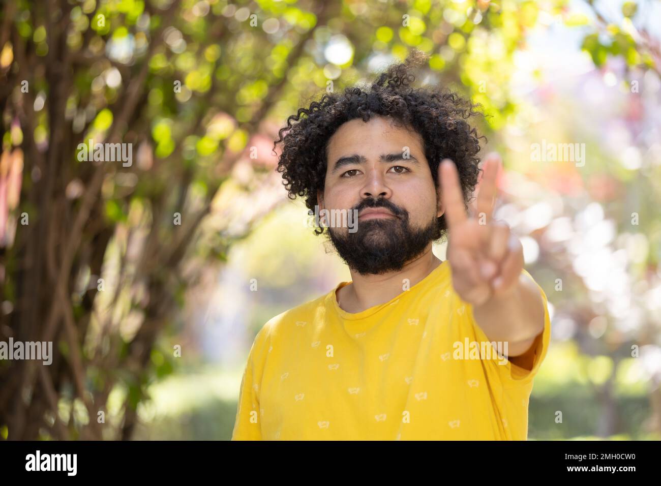 Ritratto di un uomo messicano con afro e barba che fanno segno di pace Foto Stock