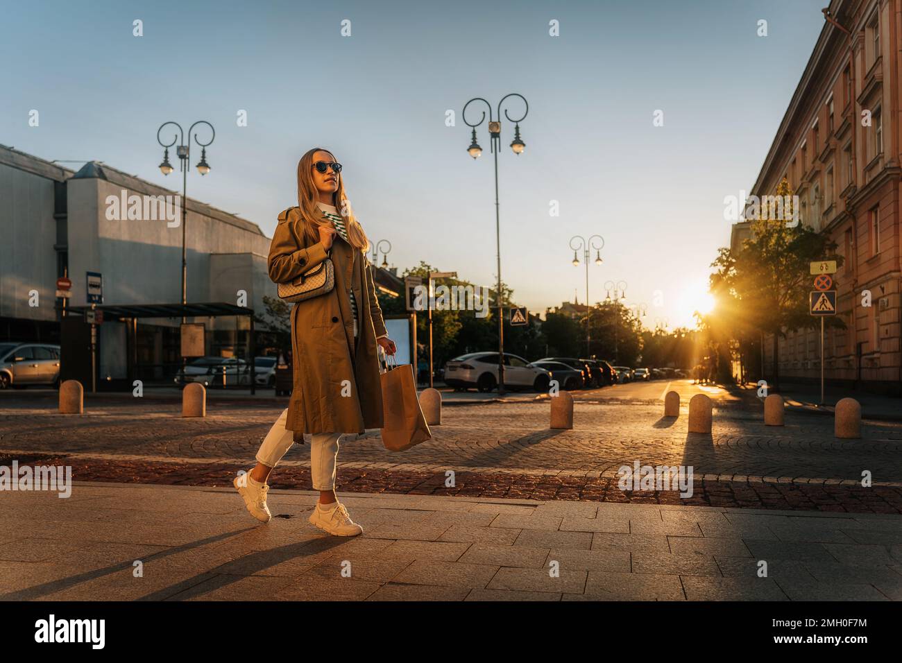 Donna cammina lungo la strada della città in serata dopo lo shopping con la borsa di carta Foto Stock