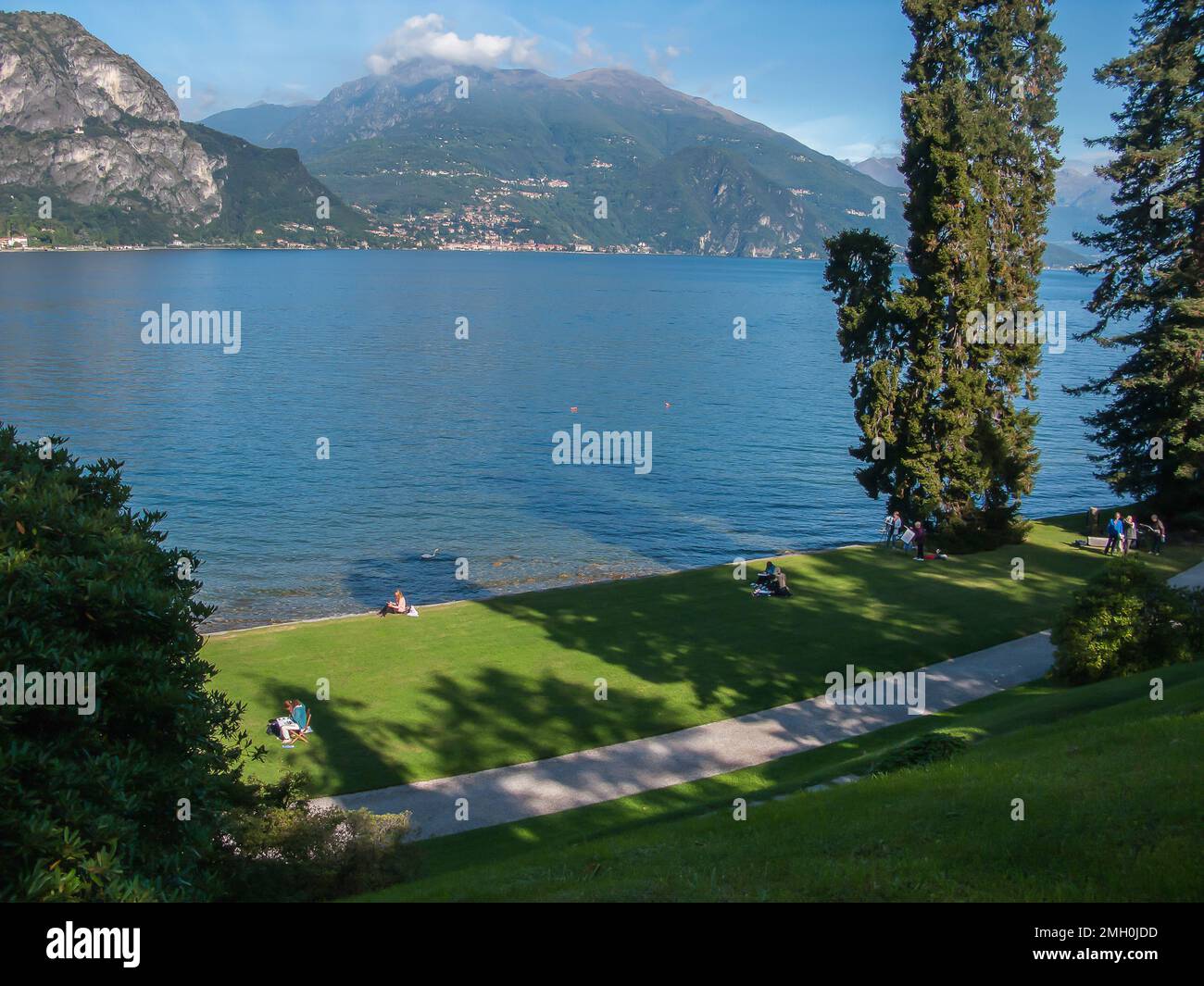 lago di Como, montagne e prato verde con erba tagliata nel parco di villa Melzi, Bellagio, Italia Foto Stock